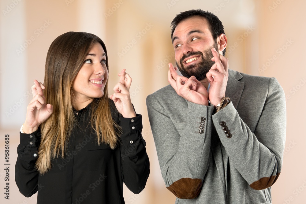 Couple with their fingers crossing over white background Couple with their fingers crossing over white background