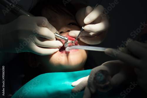 Dentist examining a patients teeth in the dentists chair under bright light