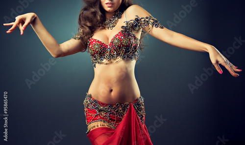 
Graceful girl dancing belly dance . Belly dance in plastic movement of the dance. Red dress for belly dance with sequins and rhinestones and jewelry