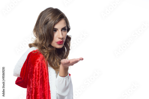 Beautiful christmas young girl dressed in red, blows