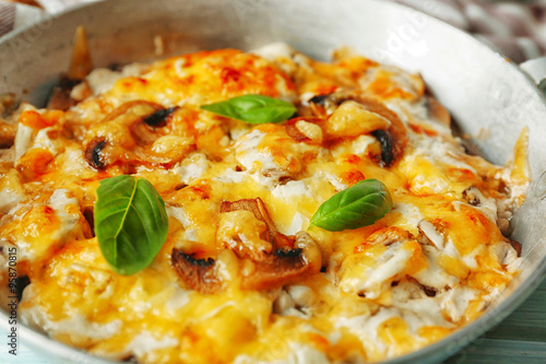 Roasted mushrooms, chicken and cheese gratin in pan, on wooden background