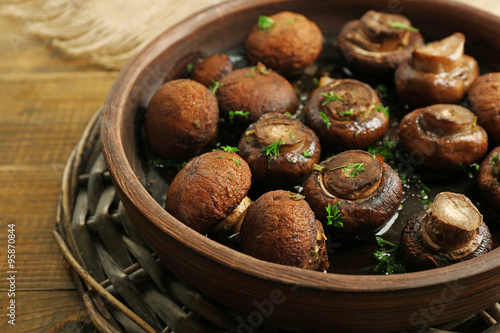 Baked champignons mushrooms with butter, parsley and roasted garlic in brown bowl