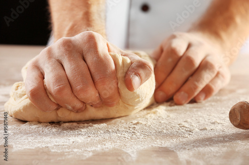 Hands kneading dough for pizza on the wooden table, close-up © Africa Studio