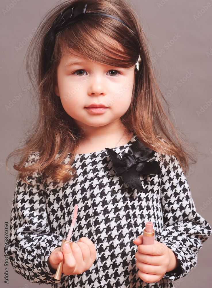Cute baby girl 4-5 year old holding lipstick i room over gray. Looking at  camera. Childhood. Stock Photo | Adobe Stock