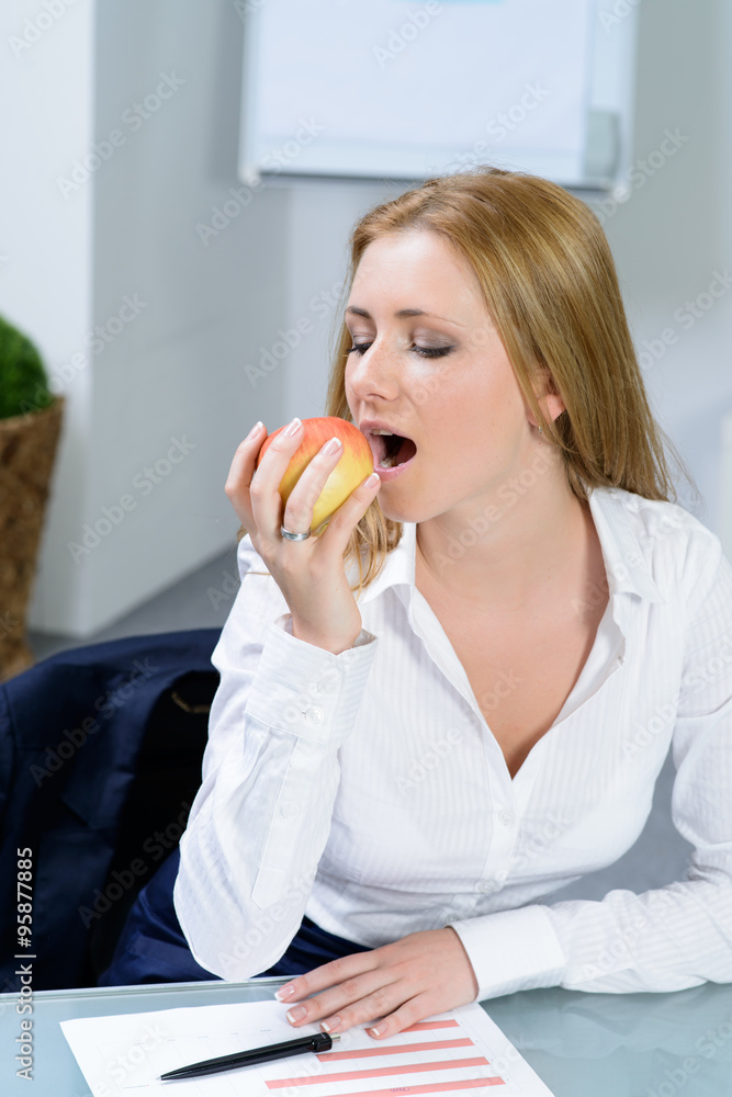 beautiful businesswoman eating an apple in office beautiful businesswoman eating an apple in office