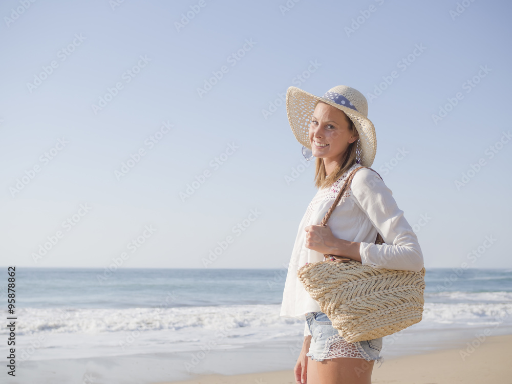 happy fashion blonde girl smiling portrait in the beach, wearing hat, a bag, shorts and white shirt, in the beach, profile photo