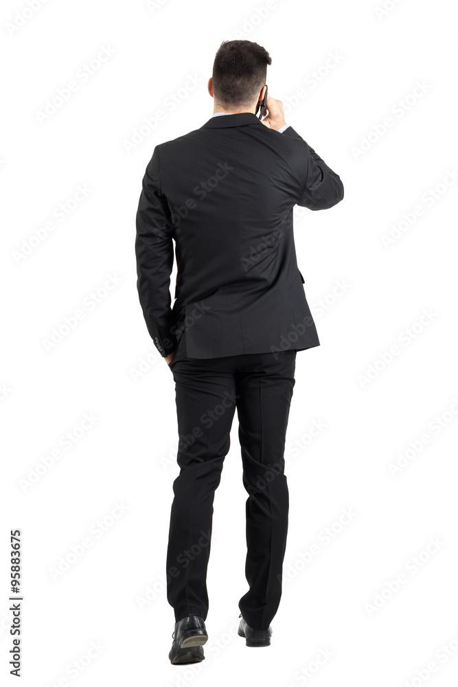 Young business man talking on the phone walking away rear view. Full body length portrait isolated over white studio background. Young business man talking on the phone walking away rear view. Full body length portrait isolated over white studio background.