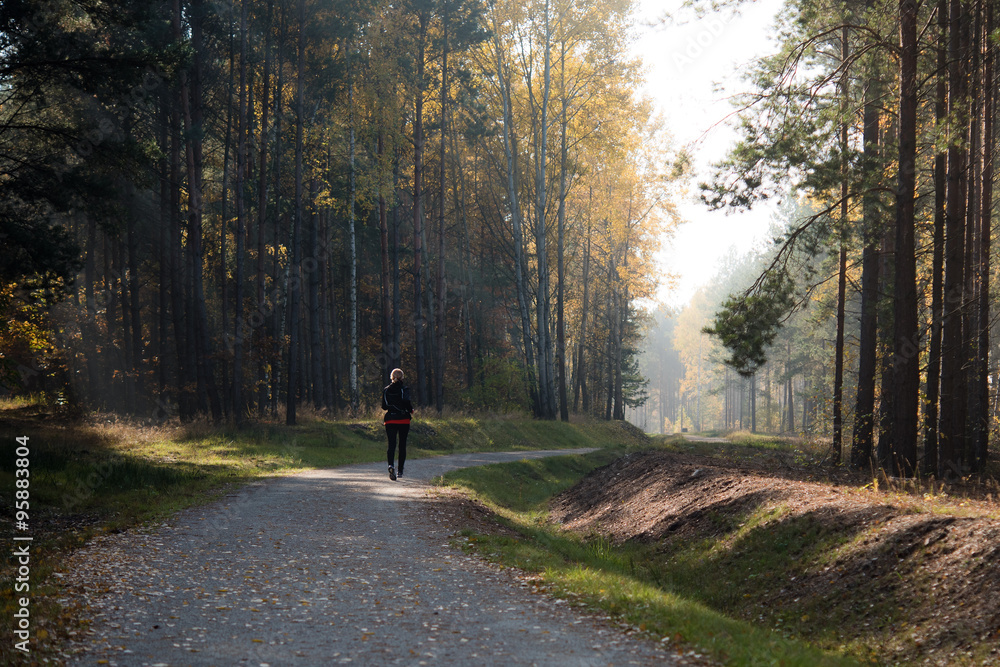Blonde woman jogging in autumn forest.
