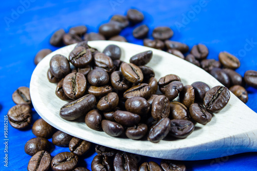 Coffee beans in wooden spoon on blue background photo