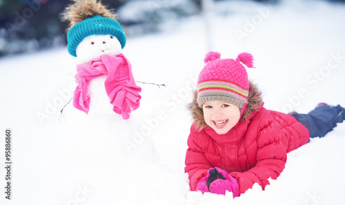happy child girl with a snowman on a winter walk