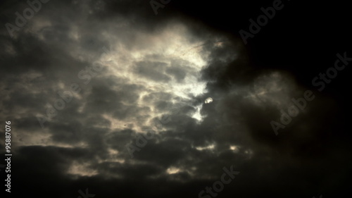 4K sun hides behind dark storm clouds time lapse with light rays photo