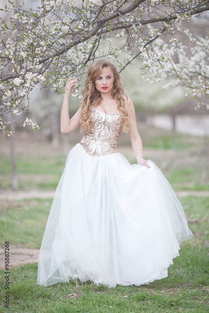 Young beautiful blonde woman in blooming garden. Bride