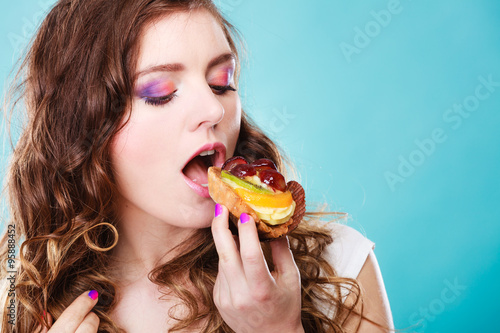Cute girl holds fruit cake in hand on blue