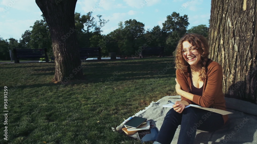 portrait of a smiling female student sitting under the tree in the park portrait of a smiling female student sitting under the tree in the park