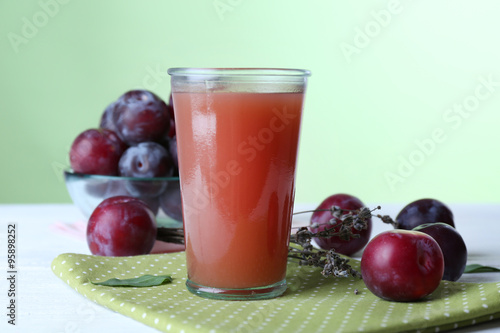 Delicious plum juice with fruits on green background