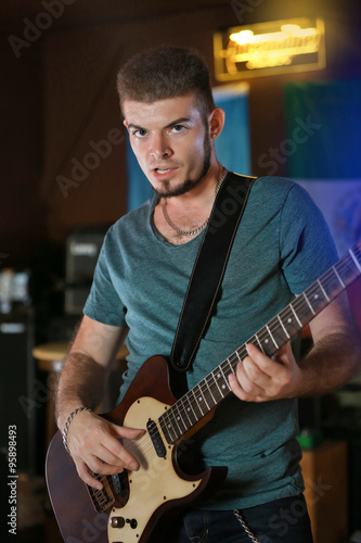 Young man playing on electric guitar at pub