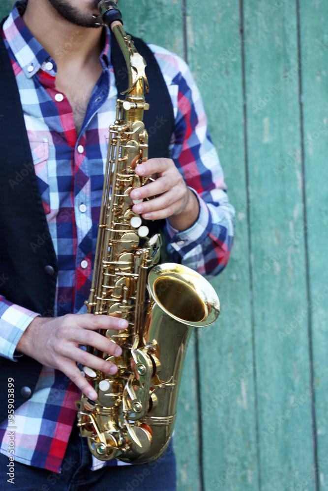Fototapeta premium The musician plays saxophone on green wooden background, close up