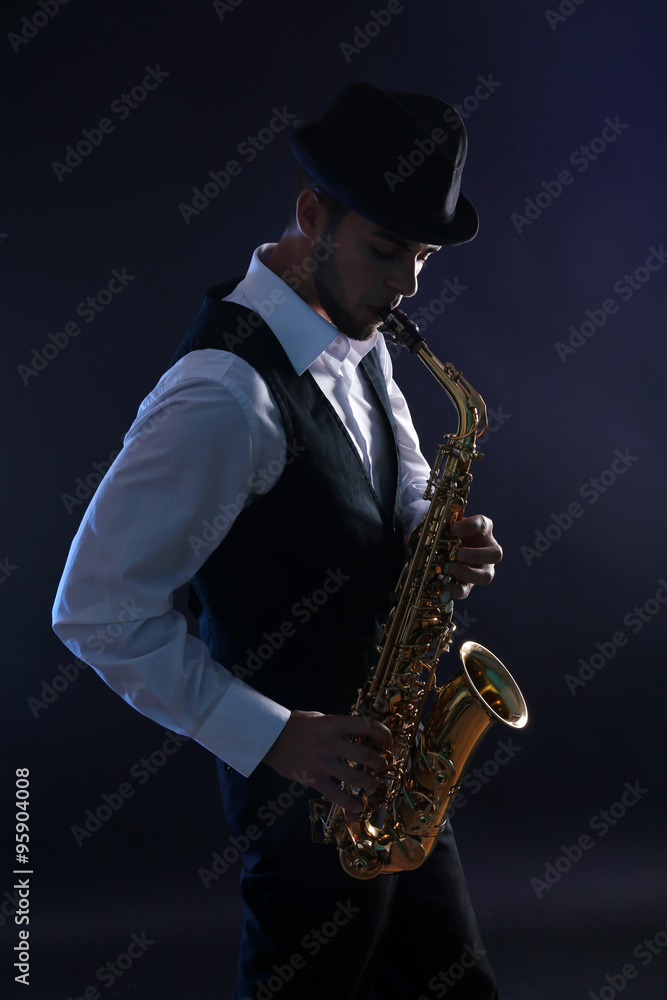 Obraz premium Elegant saxophonist plays jazz on dark background
