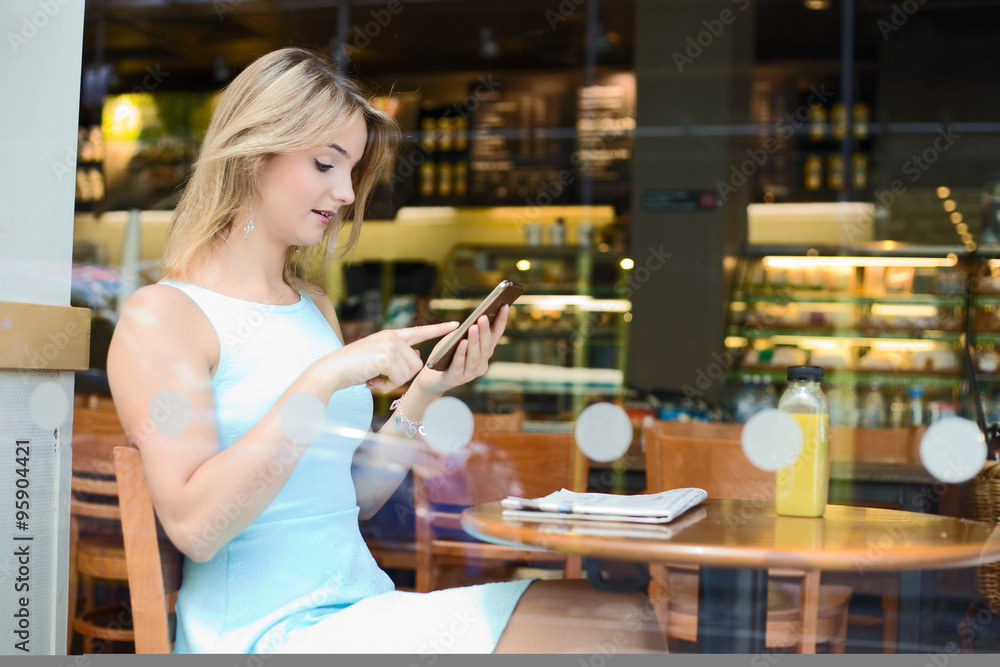 young woman sitting in a coffee shop using her phone