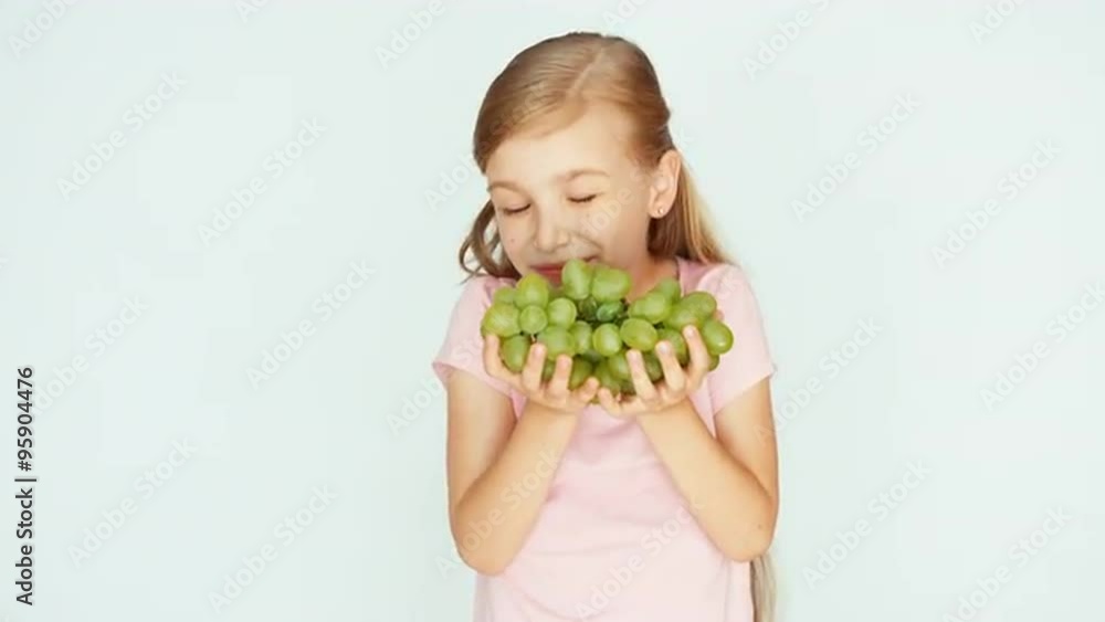 Girl holding grapes in the palm. Child sniffing grapes and laughing Girl holding grapes in the palm. Child sniffing grapes and laughing