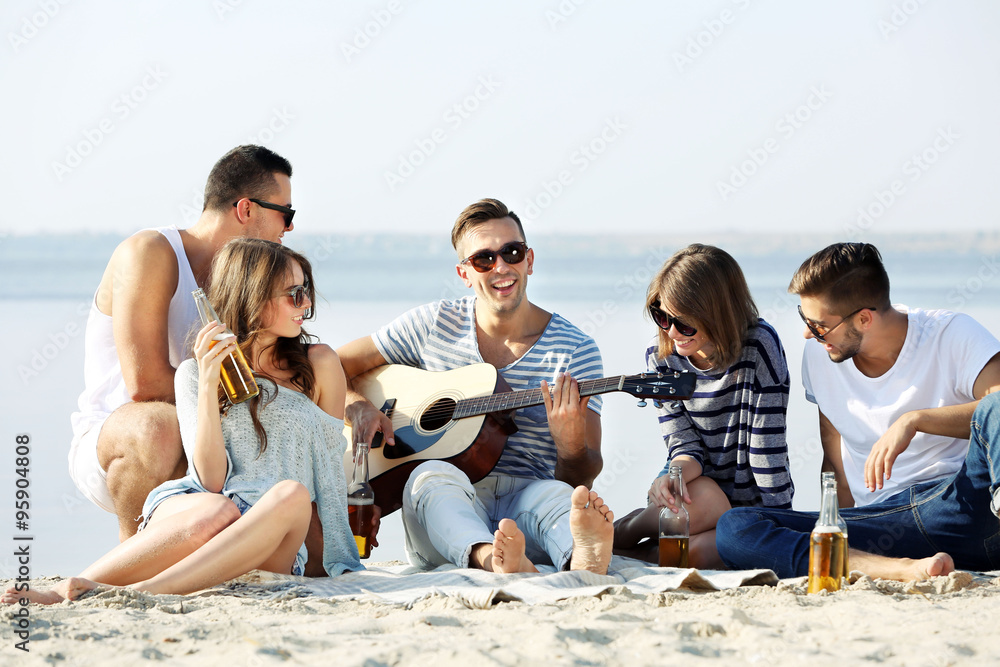 Young people with guitar singing songs on the riverside Young people with guitar singing songs on the riverside
