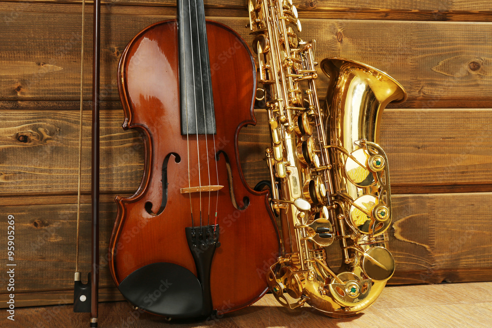 Naklejka premium Violin and saxophone on wooden background