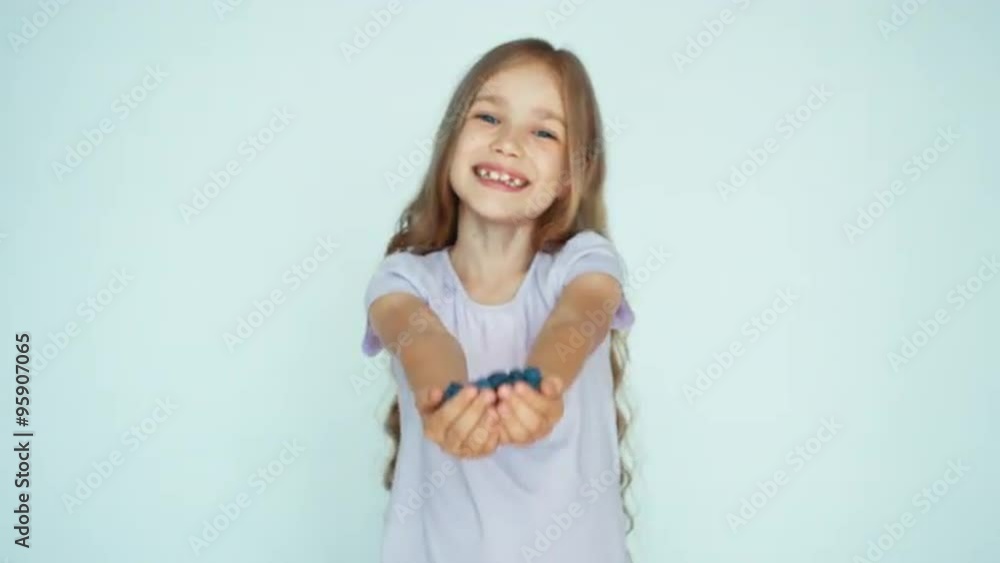 Girl holding in handful blueberry sniffing and showing at camera on the white background. Happy child with fruits Girl holding in handful blueberry sniffing and showing at camera on the white background. Happy child with fruits