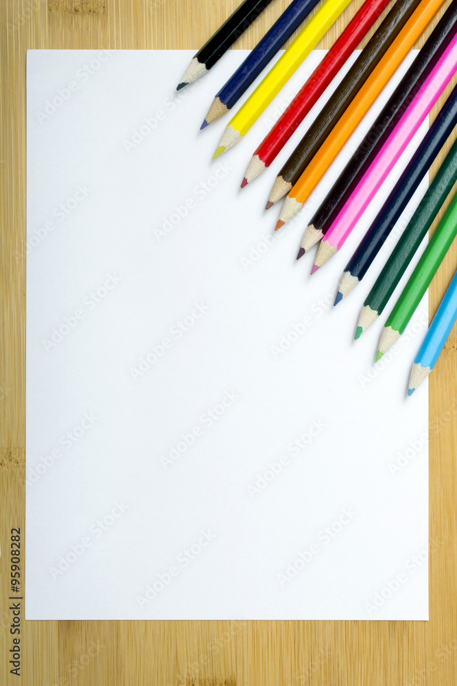 Fototapeta premium Blank paper and colorful pencils on the wooden table.