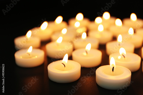 Alight candles in a row on black background  blurred