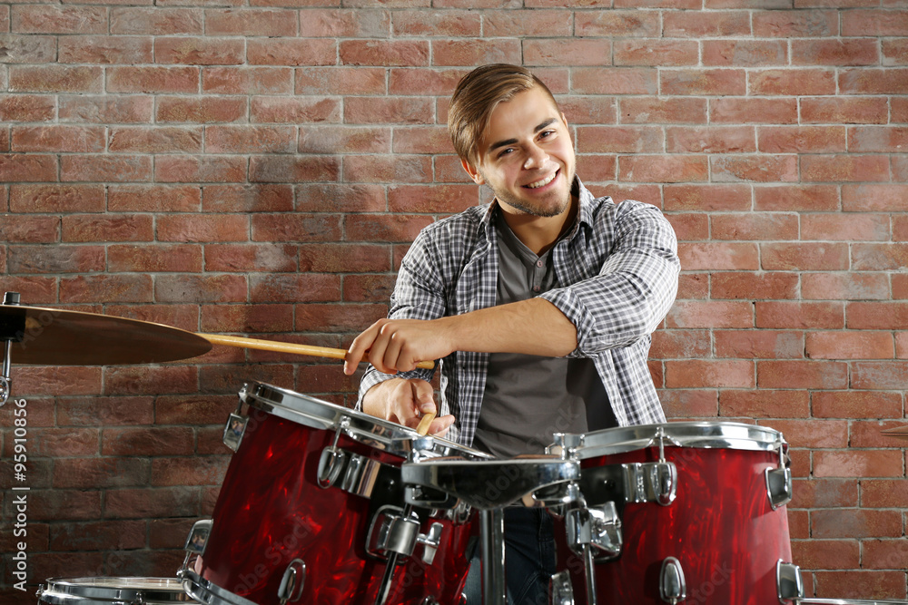 Musician playing the drums on brick wall background Musician playing the drums on brick wall background