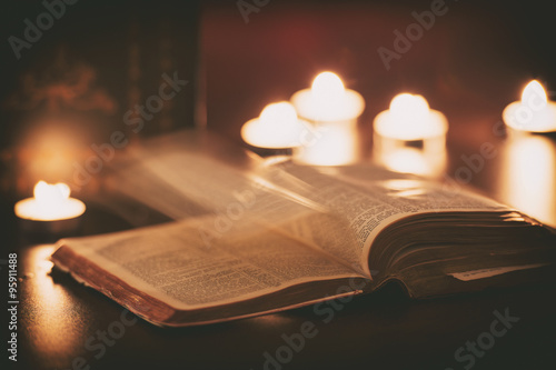 Bible with ghost pages turning and candles in the background 