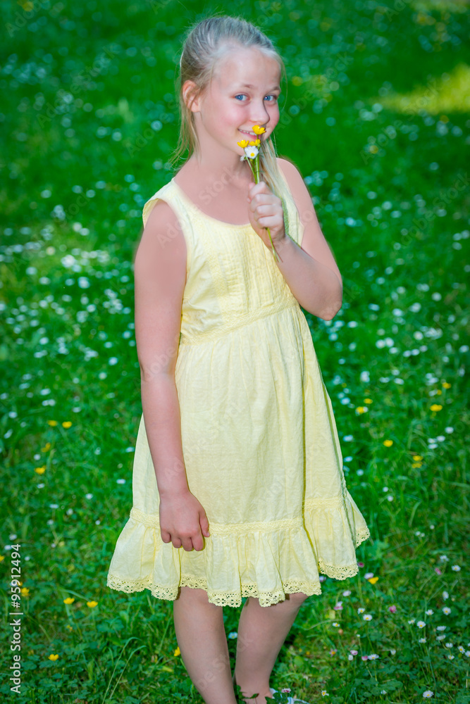 ein kleines Mädchen mit blauen Augen riecht an ein paar Blümchen Stock  Photo | Adobe Stock