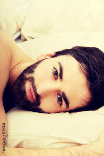 Young muscular man lying in bed.