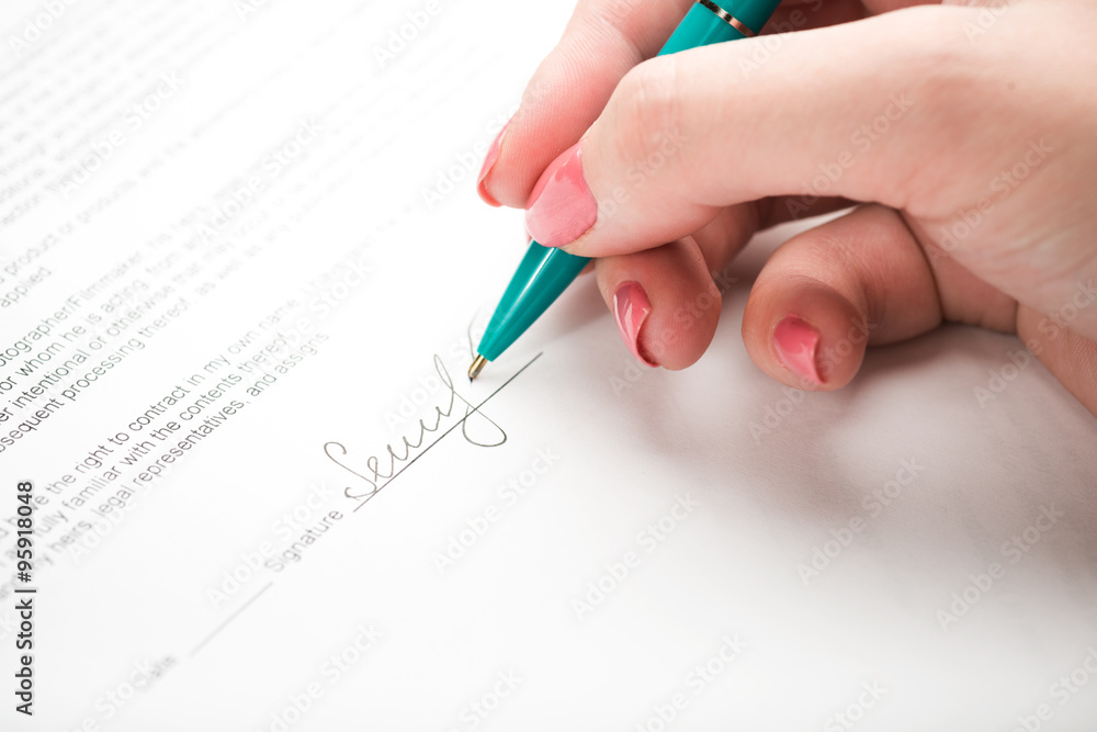 female hand signing a contract. female hand signing a contract.