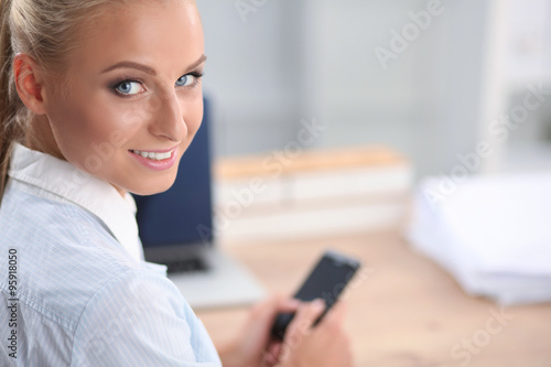 Businesswoman sending message with smartphone sitting in the office © lenets_tan