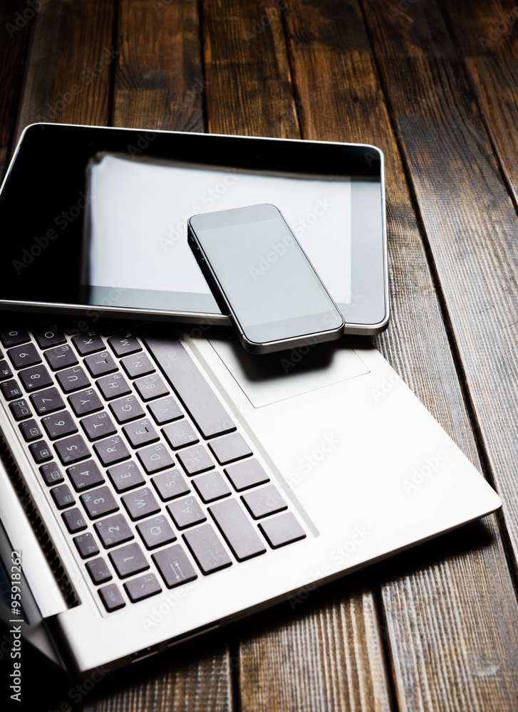Laptop with phone and tablet pc on wooden desk Laptop with phone and tablet pc on wooden desk