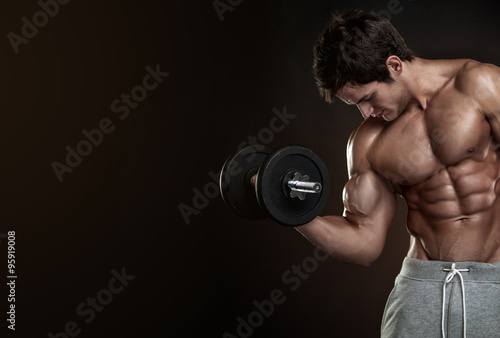 Muscular bodybuilder guy doing exercises with dumbbells over bla