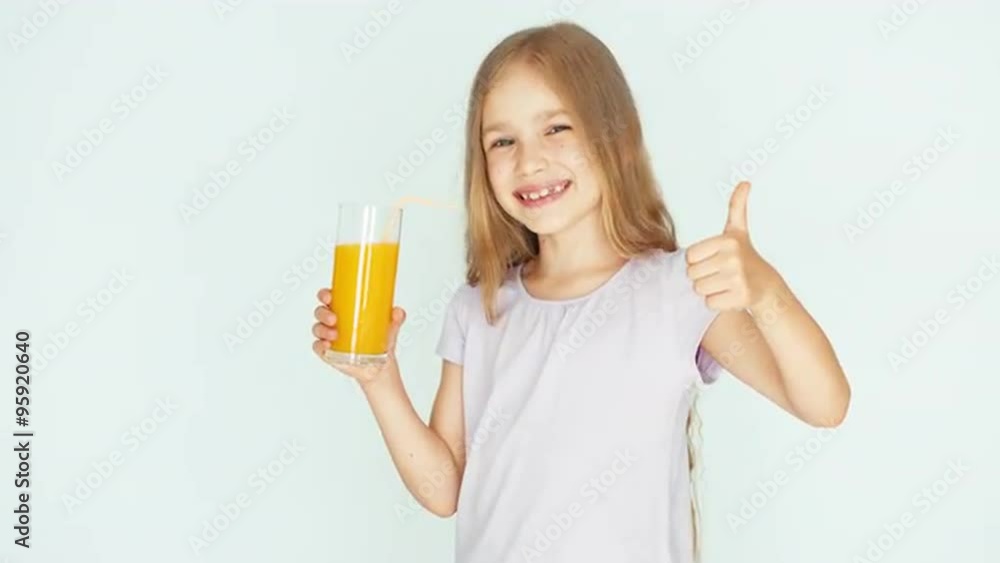 Girl holding glass of orange juice and laughing at camera. Girl with beautiful blonde hair on a white background. Thumb up. Ok Girl holding glass of orange juice and laughing at camera. Girl with beautiful blonde hair on a white background. Thumb up. Ok