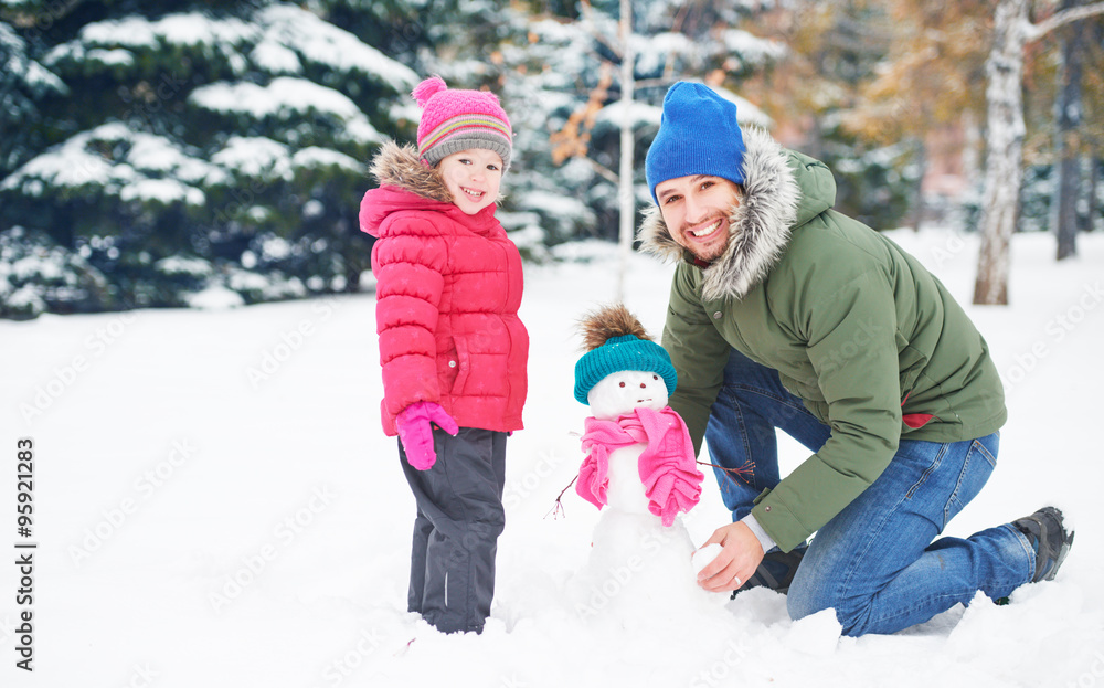 Happy family father and child girl makes snowman in winter