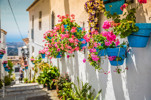 Fototapeta Picturesque street of Mijas with flower pots in facades. Andalus