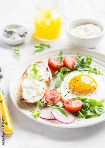 fried egg  fresh vegetable salad and a grilled cheese sandwich on a light plate on white background - healthy Breakfast