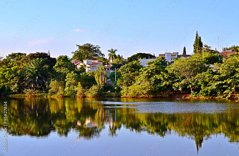 Tropical landscape with trees, lake, blue sky and reflection in water