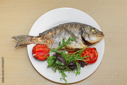Photos Grilled dorado fish with tomatoes, arugula and basil on white pl