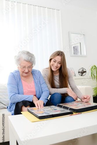 elderly woman with her young granddaughter at home looking at memory in family photo album © W PRODUCTION