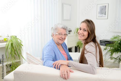 old woman at home with cheerful young girl spending time together with a laptop computer