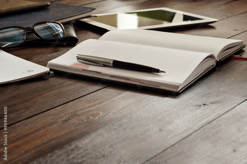 Open notepad with a pen on a wooden office table Open notepad with a pen on a wooden office table