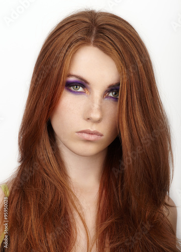 Closeup portrait of young calm beautiful redhead woman with gorgeous hair and violet eyes makeup