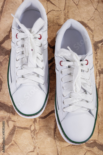 Pair of White Fashionable Laced Trainers On Wooden Surface.