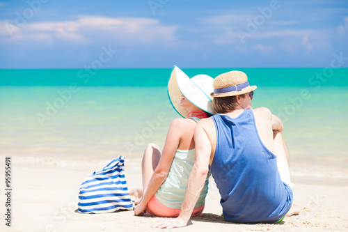 back view of romantic couple in bright clothes enjoying sunny day at tropical beach photo