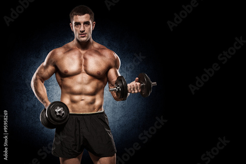 Handsome man with big muscles  posing at the camera in the gym